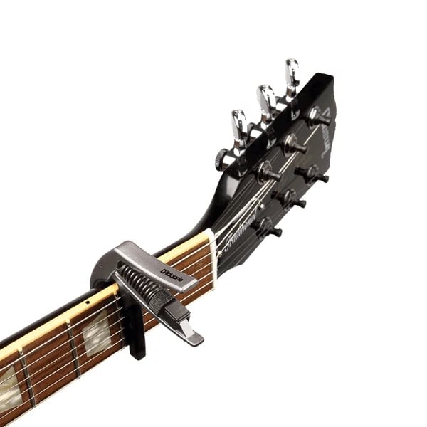 Close-up of a guitar headstock and fretboard with a capo clamped on the neck, chrome tuners visible against a white background.