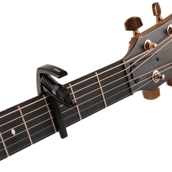 Capo clamped onto the fretboard of a guitar neck near the headstock.